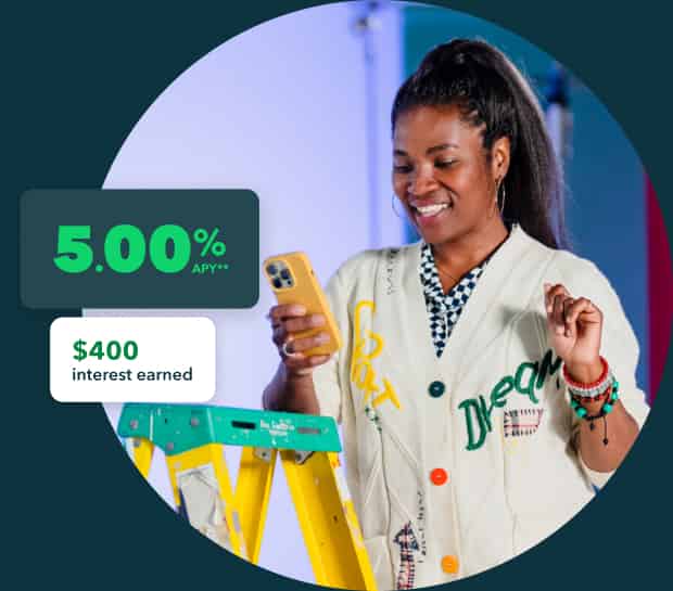 An entrepreneur looks at QuickBooks Money on her phone. She gets 5.00% APY and earned $400 in interest last month.