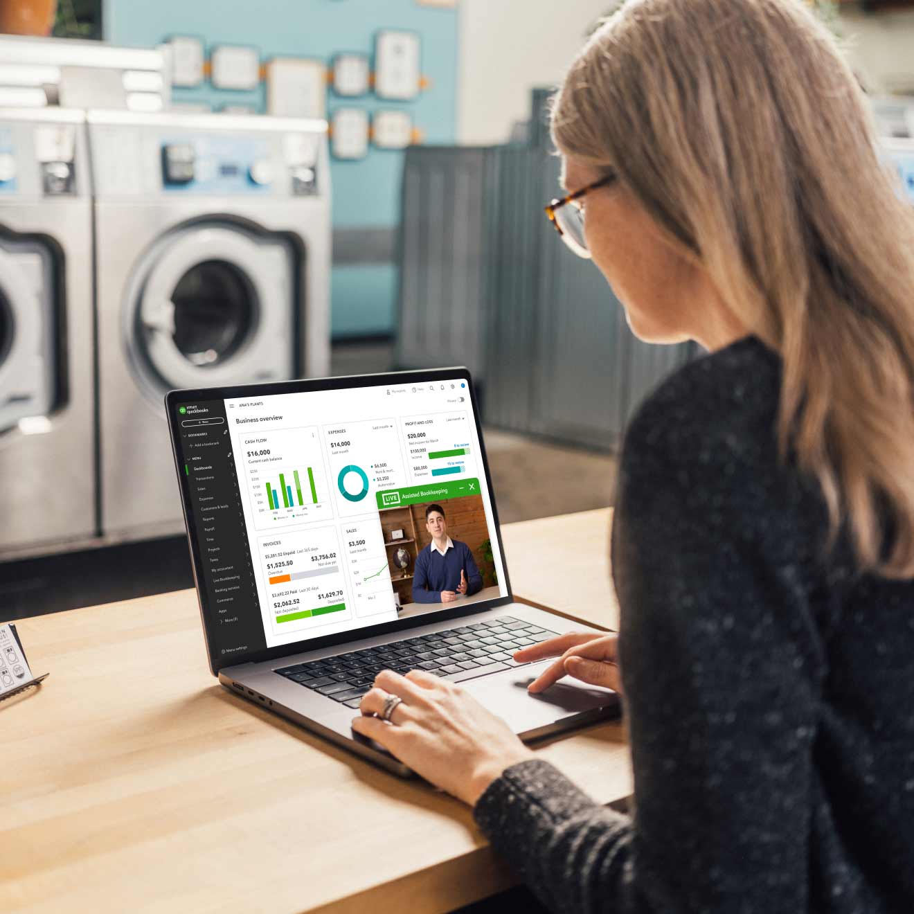 A laundry service business owner is sitting in front of a laptop on a video call with a QuickBooks Live bookkeeper. 