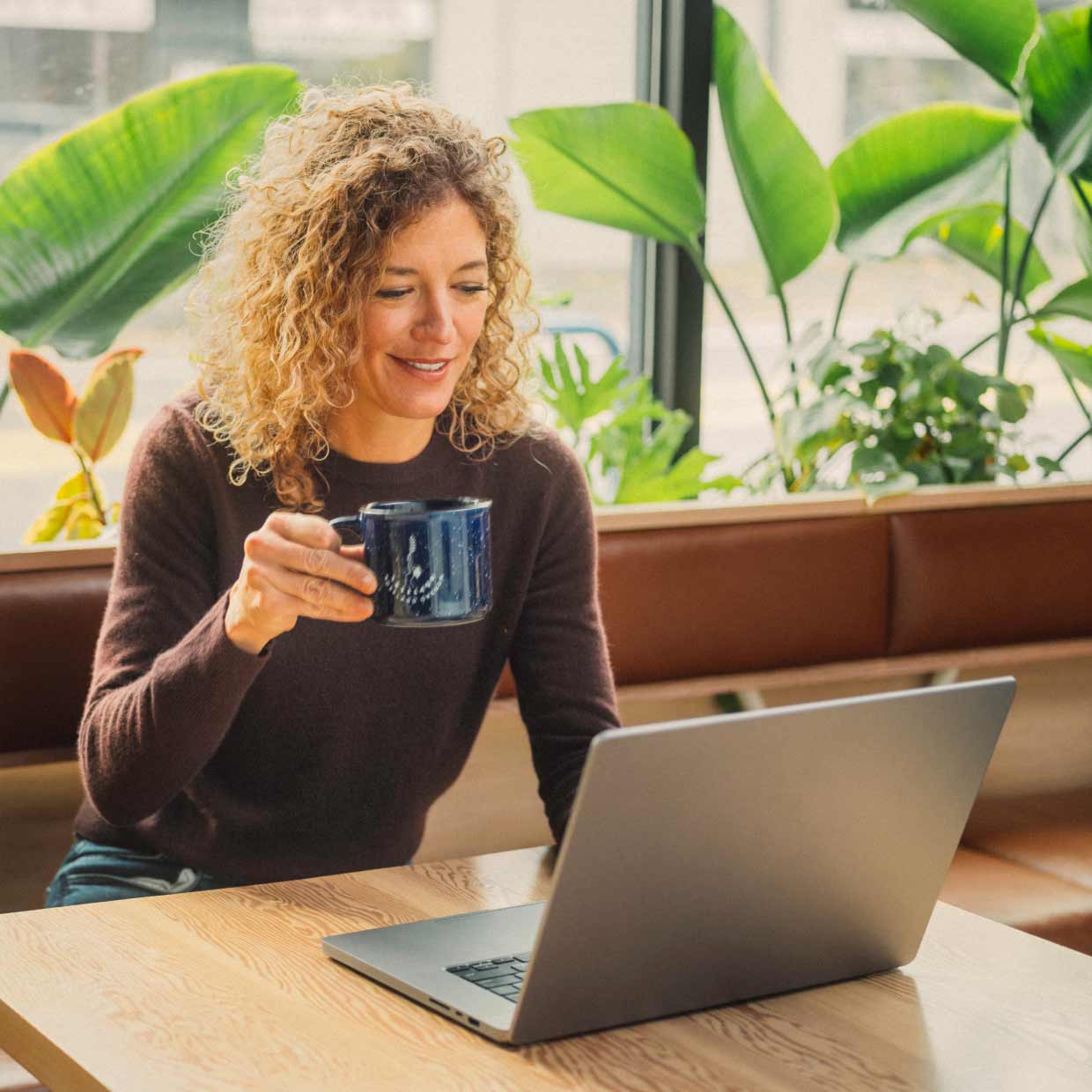 A business person is sitting at a desk reviewing her business on a laptop.