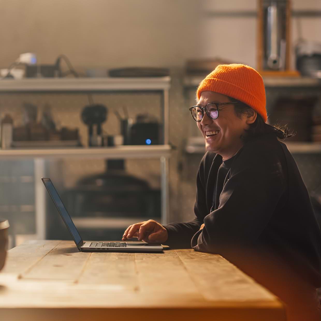 Smiling business owner at a laptop scheduling a bill payment.
