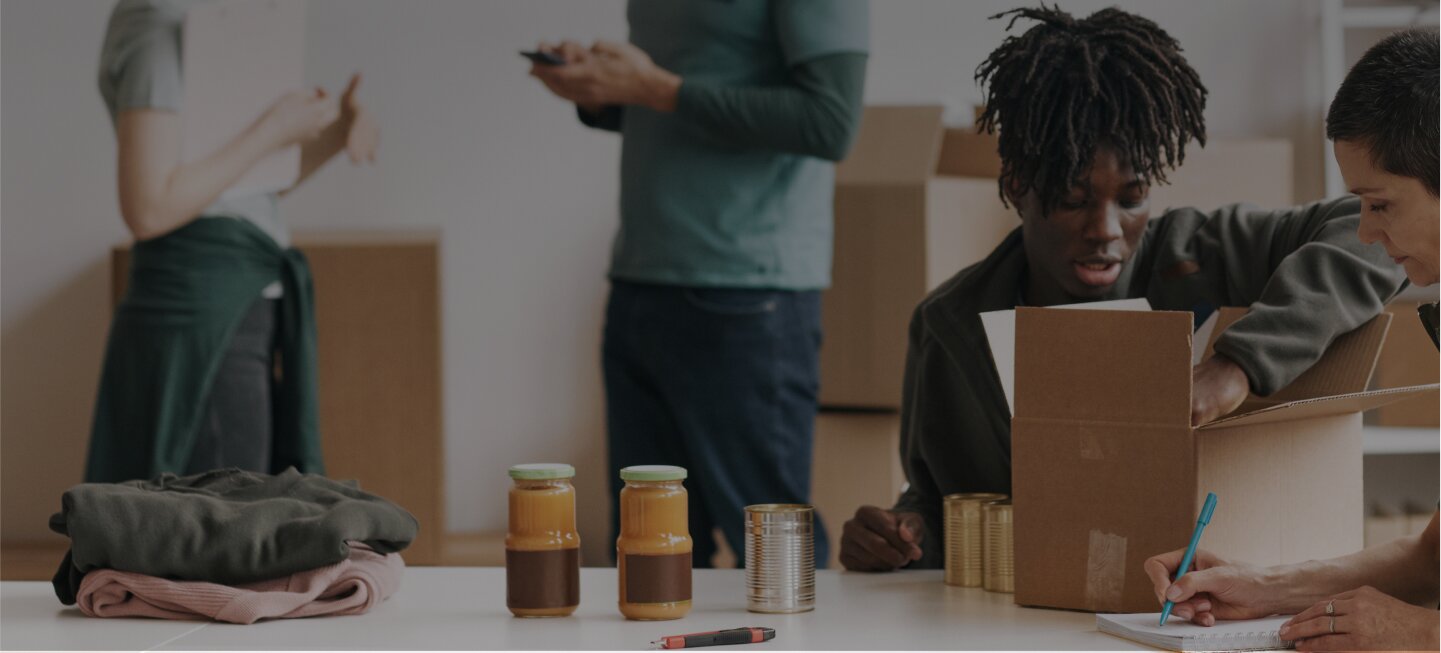 A person sitting at a table with a bunch of boxes of stuff.
