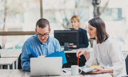 Two law firm employees working at a shared desk space.