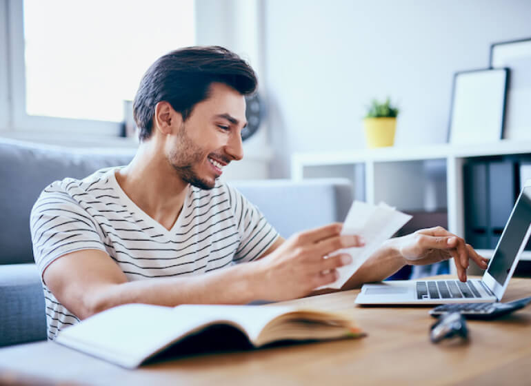 Person smiling and entering information into QuickBooks on their laptop.