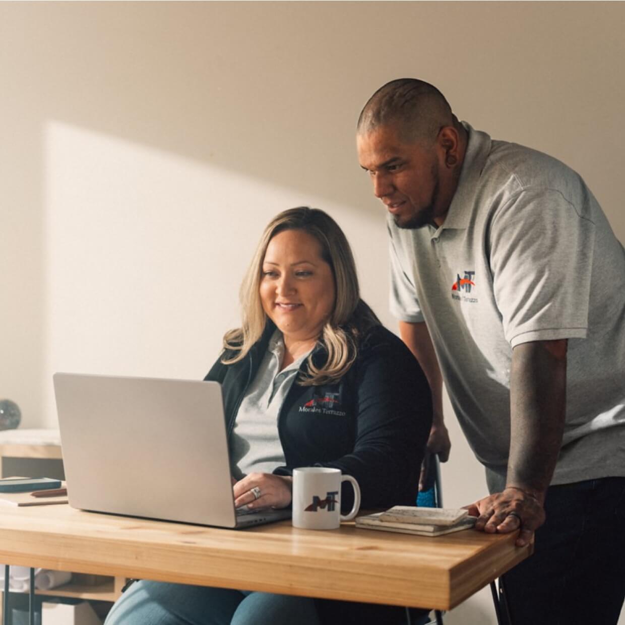 Man and woman working together at the laptop in the office. Man is pointing at the screen.