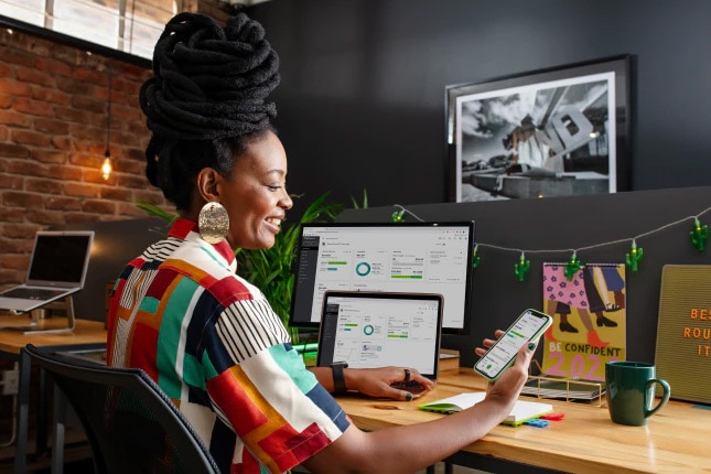 Woman using QuickBooks accounting software on multiple devices.